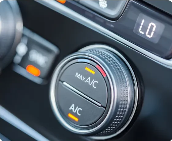 Close-up of a car dashboard showing the air conditioning control knob set to maximum A/C, with illuminated orange indicators and a digital display showing LO in the background. Auto A/C & Heater Repair In Millersport, OH At Kreager Tire and Service