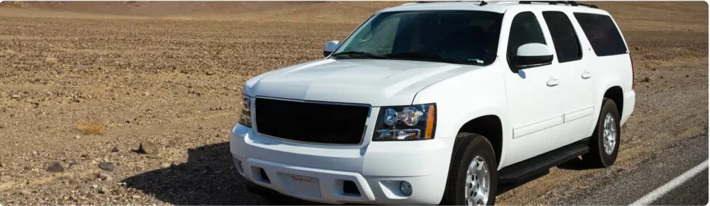 A white SUV is parked on the shoulder of a road next to a barren, desert landscape under a clear sky. Chevy Repair In Millersport, OH At Kreager Tire and Service