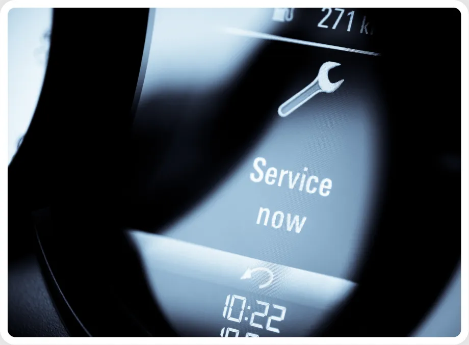 A car dashboard display shows a wrench icon and the message Service now, indicating that vehicle maintenance is required. The image is slightly blurred and framed with rounded corners. Engine Diagnostics & Repair In Millersport, OH At Kreager Tire and Service