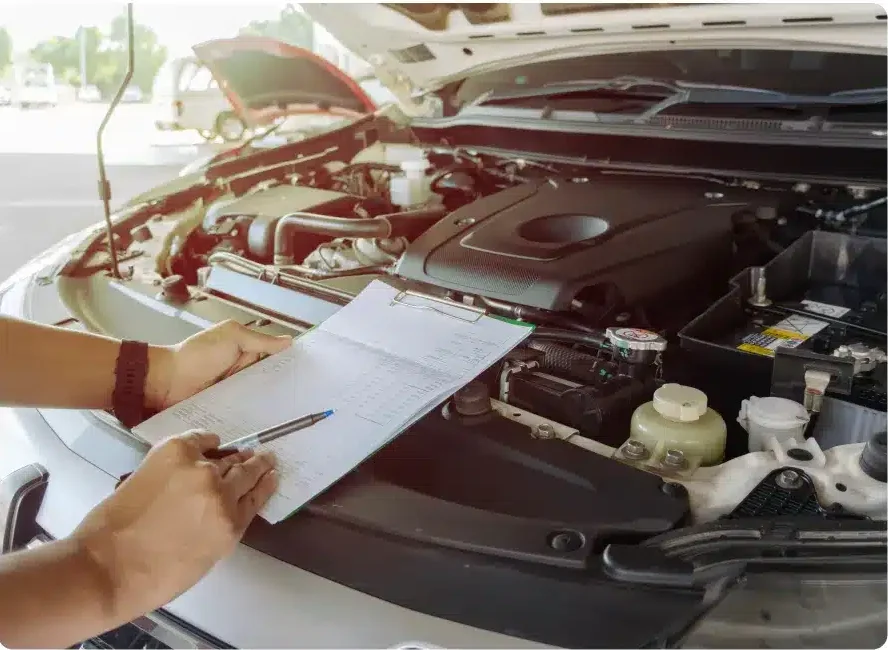 Close-up of a technician taking notes on paper while inspecting a car engine during vehicle maintenance in Millersport, OH at Kreager Tire and Service.